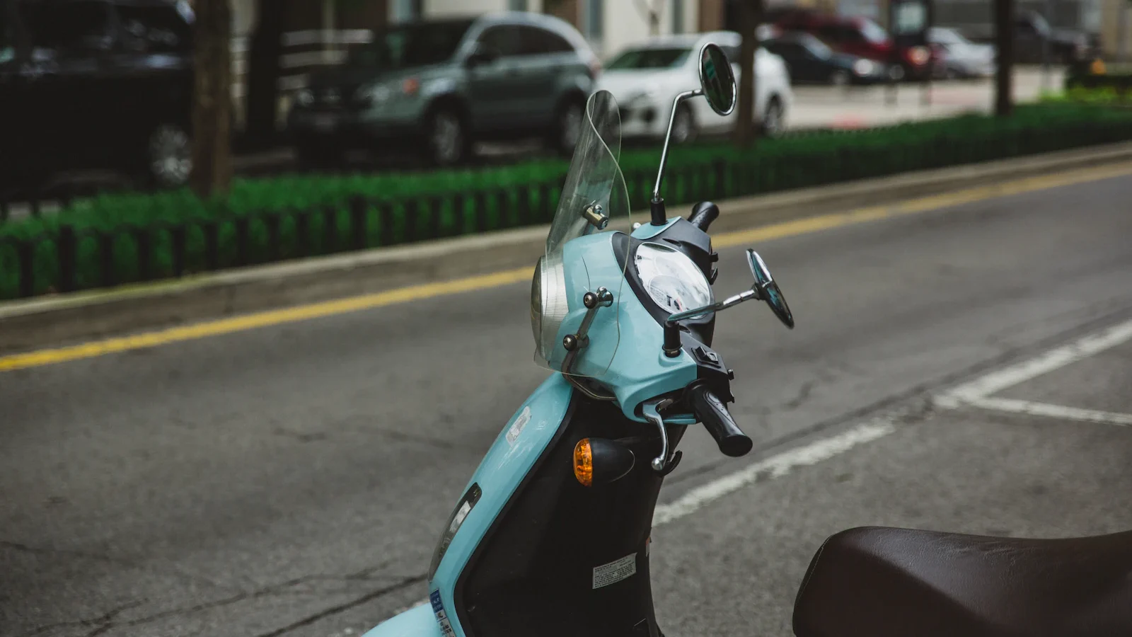 Phần đầu xe tay ga màu xanh nhạt với gương và kính chắn gió bên đường